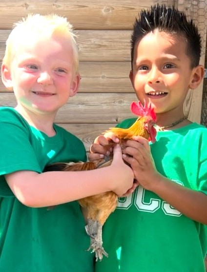 2 elementary kids holding a chicken